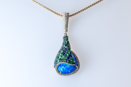 A 14k yellow gold pendant set with Opal, Sapphires, Diamonds, and Tsavorites.